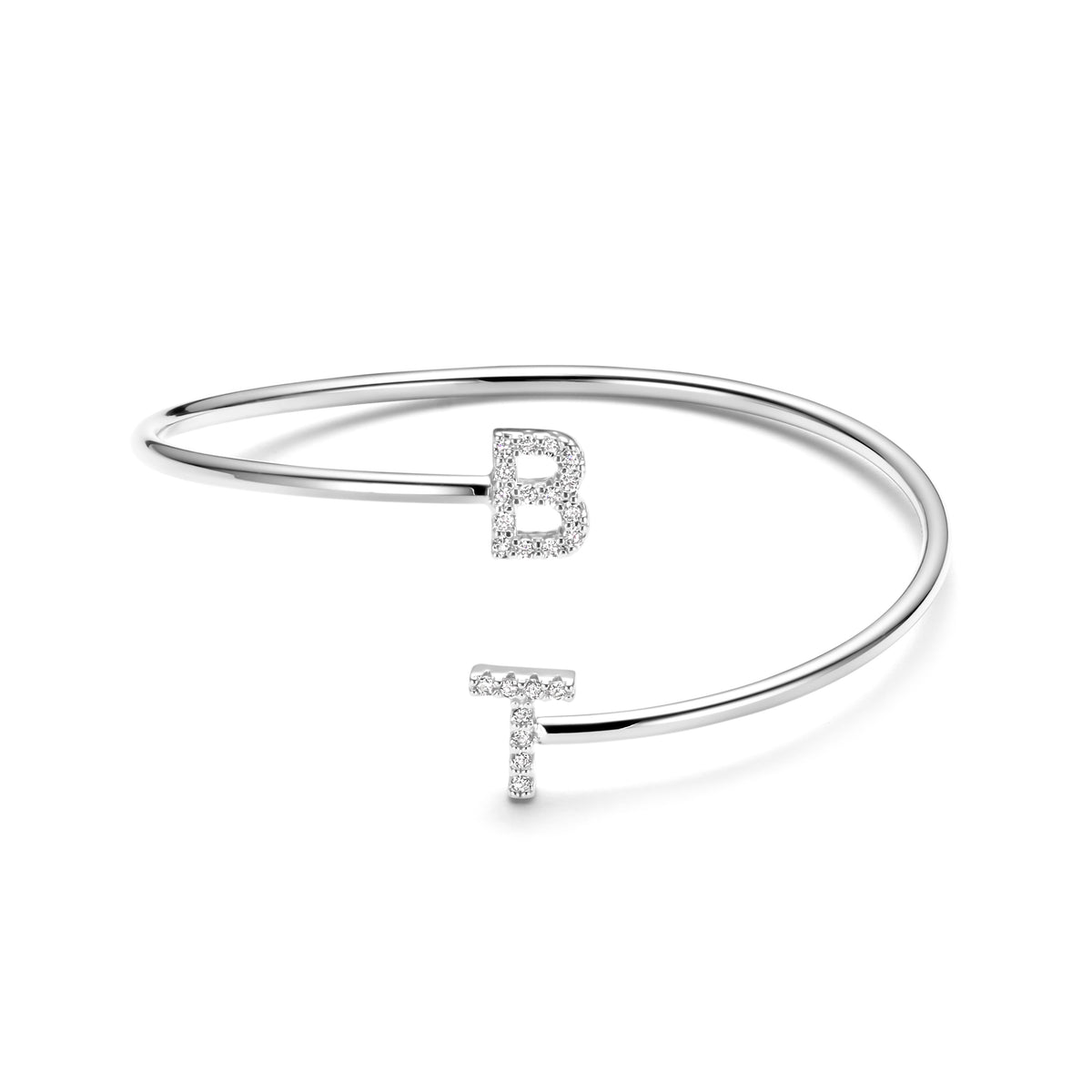 Een zilverkleurige Twisted-armband met verspringende uiteinden en glinsterende letters B en T op wit.